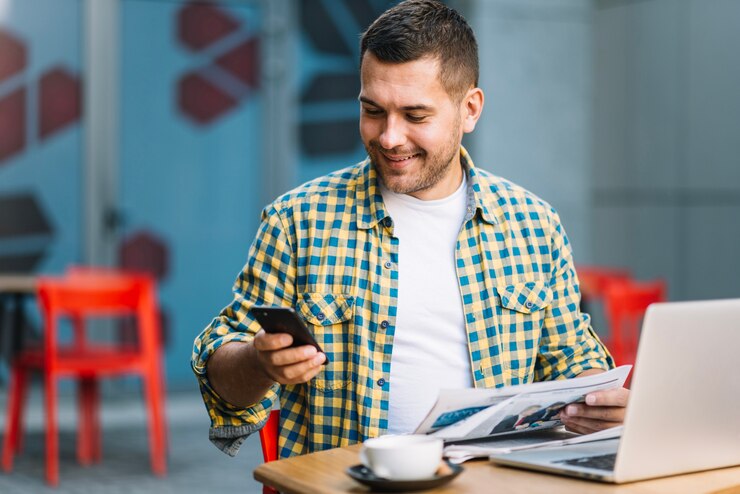 man-with-laptop-using-smartphone-cafe